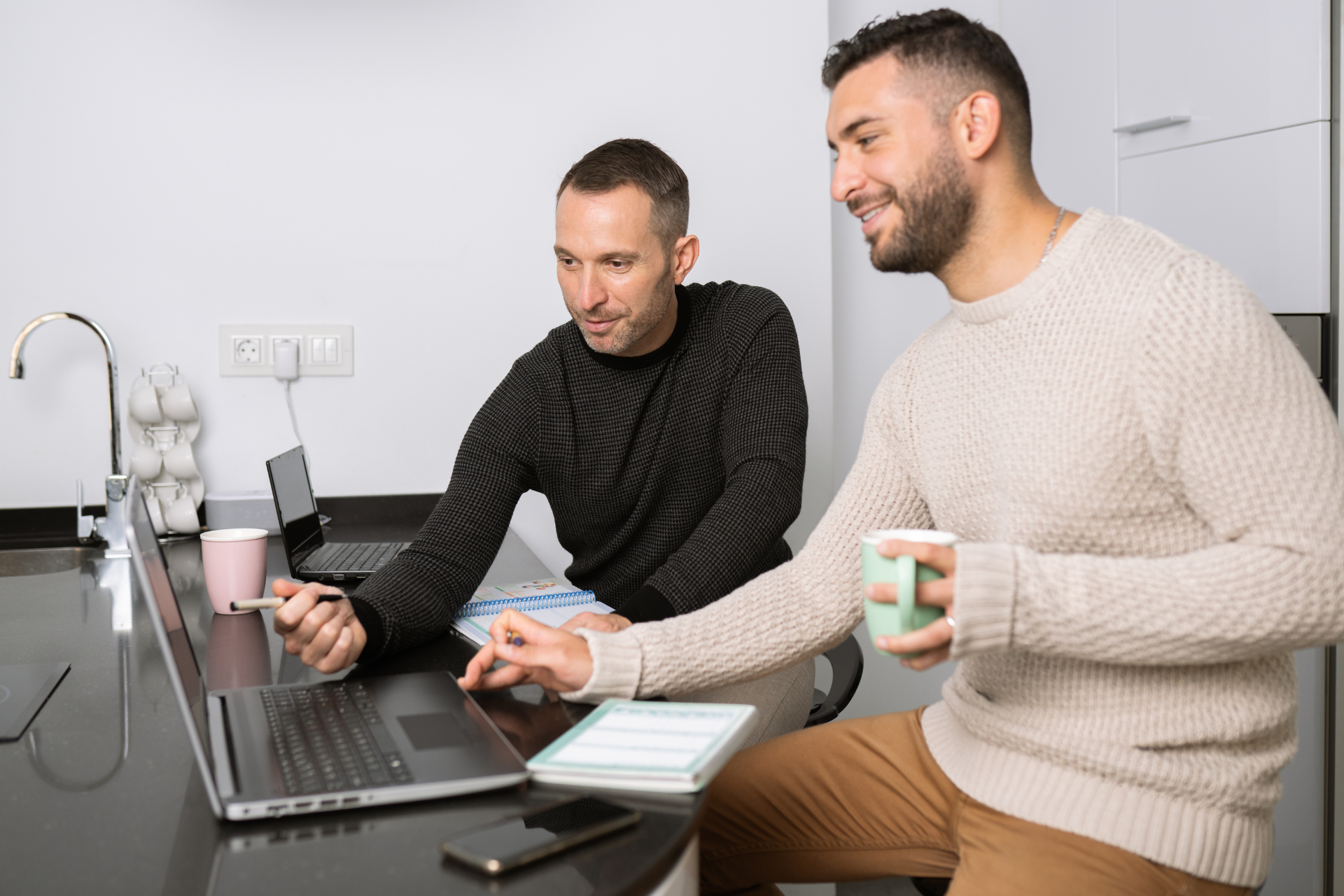 2 people at a desk looking at a laptop together