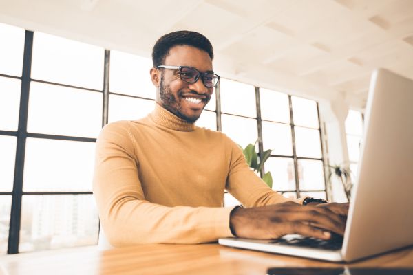 person seated using laptop and smiling