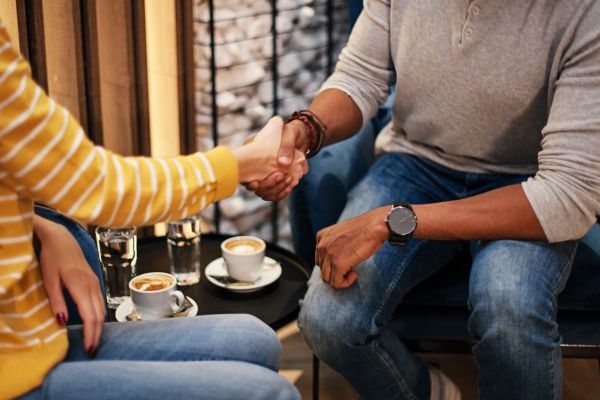 People shaking hands, seated.