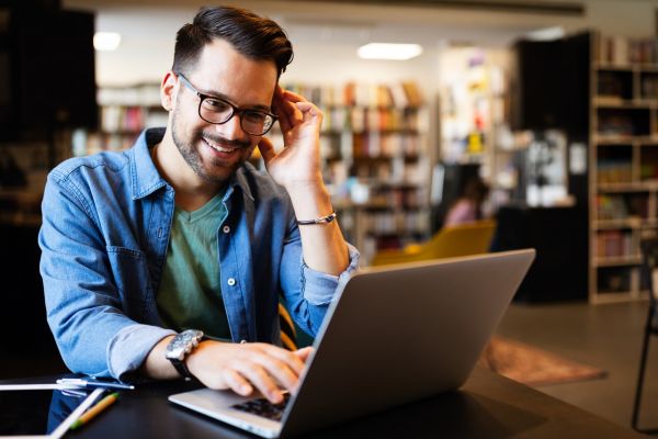 Person seated at desk looking at laptop.