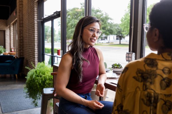 Two people seated at bar stools and tall counter engaged in conversation